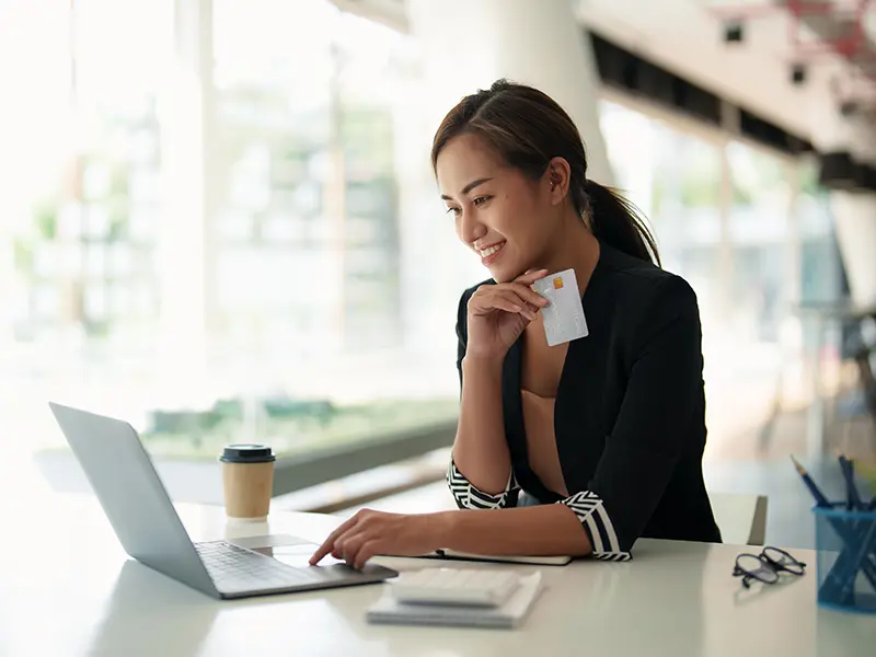 woman holding card on laptop